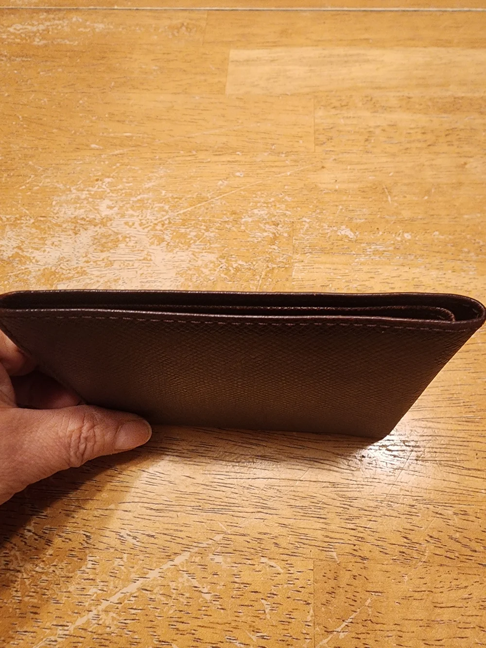 burgandy Louis Vuitton Taiga leather bifold wallet featuring a debossed LV